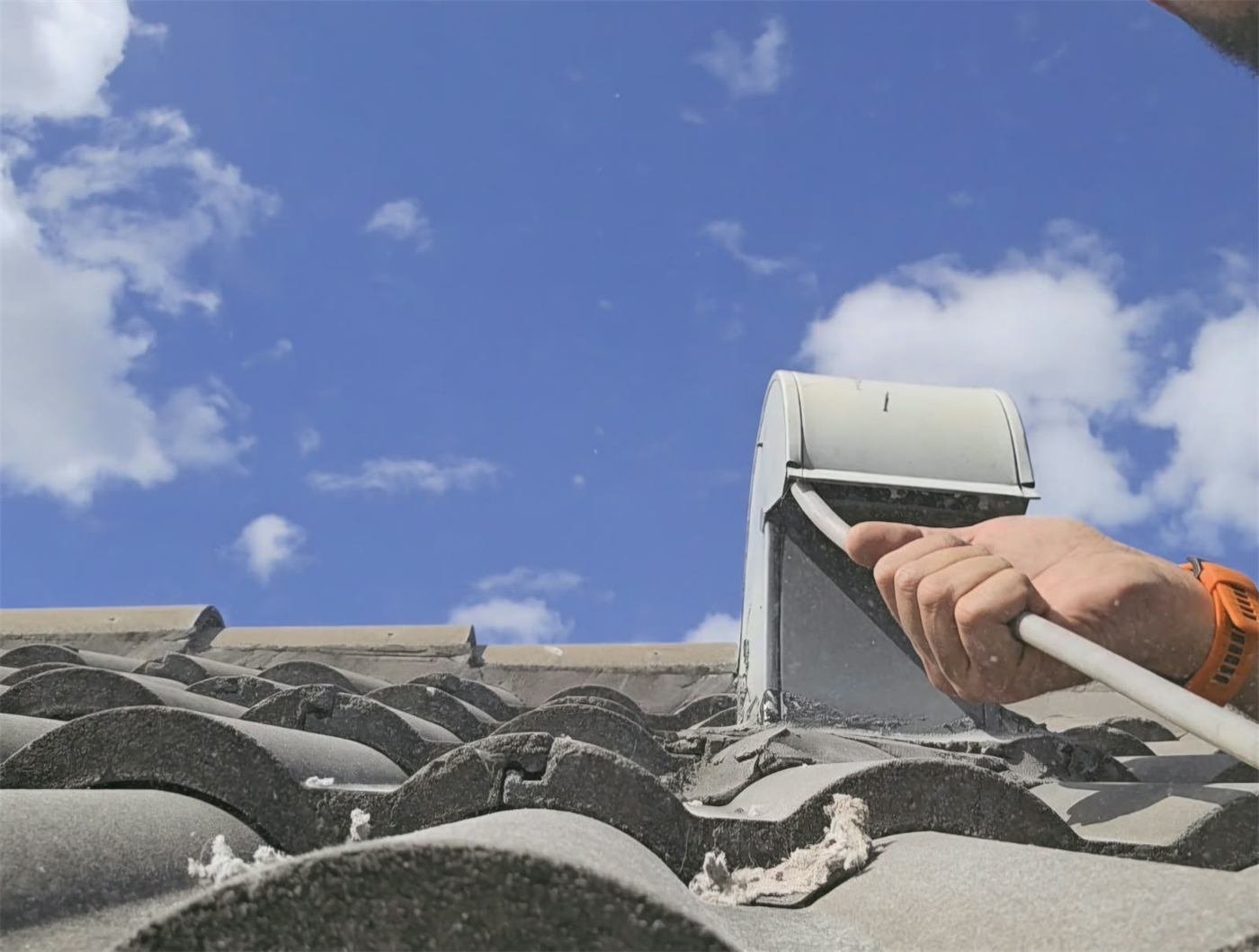 Technician cleaning a rooftop dryer vent on a Miami home